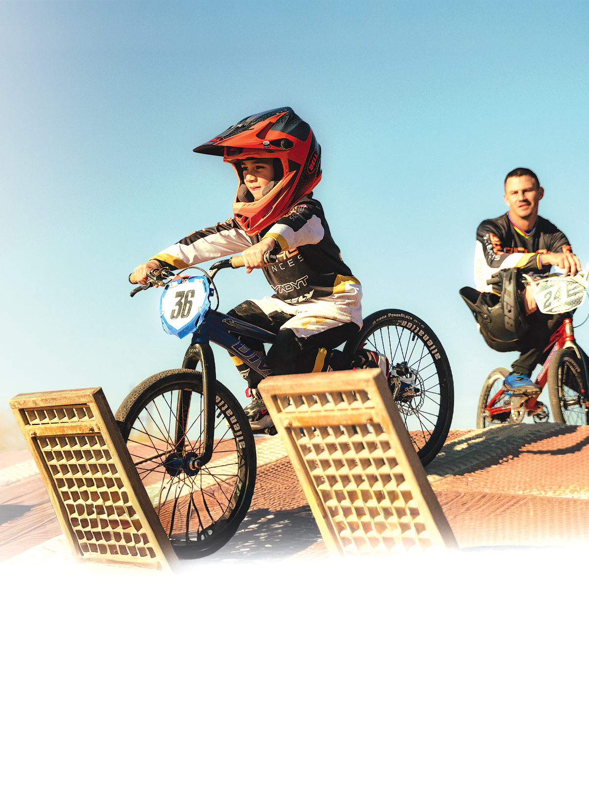 Young BMX rider staged at the race gate with a proud father watching before the start.