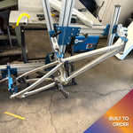 Another angle of Divine BMX bike being assembled in a jig, showcasing precision build process.